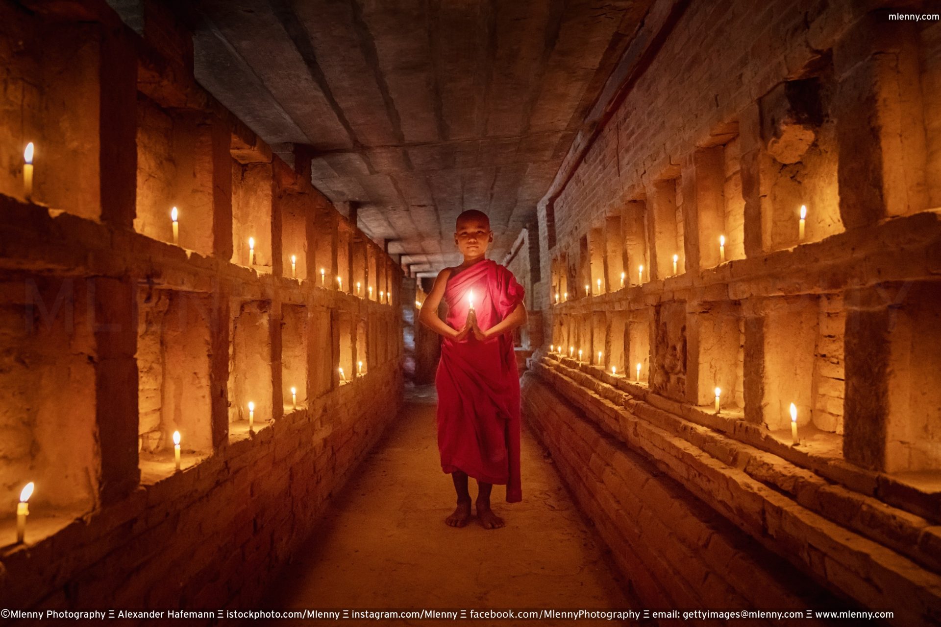 Novice Monk praying inside temple full burning candles Bagan Myanmar