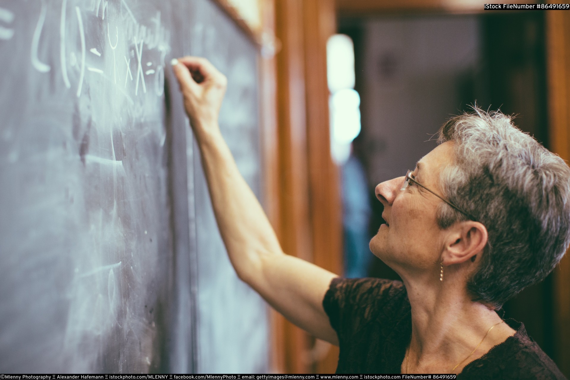 Mathemathics professor at chalkboard writing formula